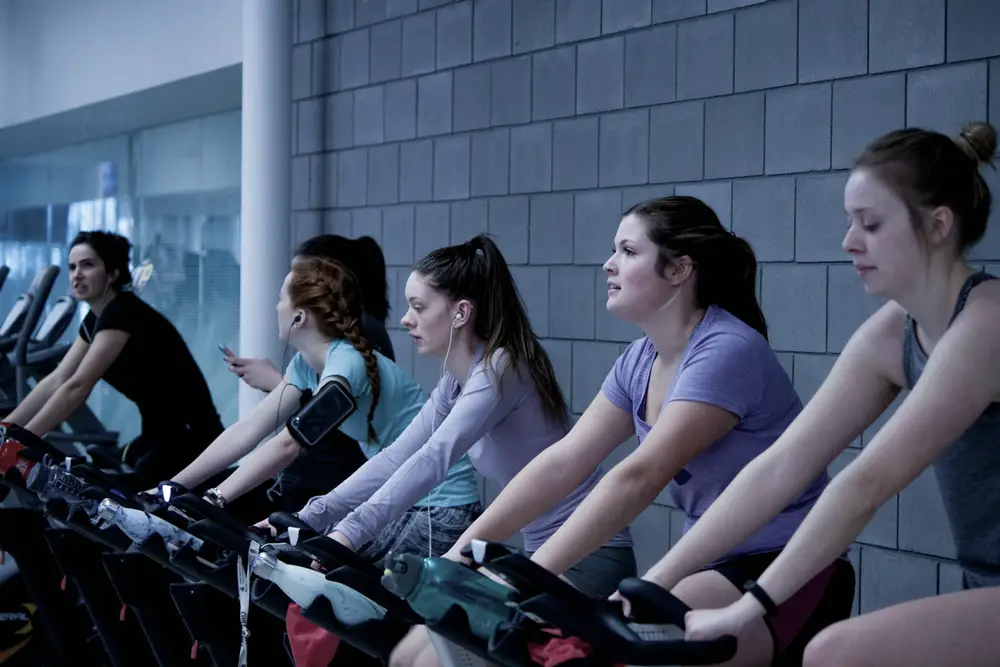 Clase de cycling con varias personas pedaleando en bicicletas fijas