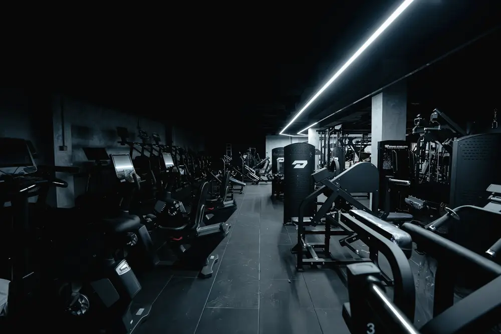 Piso de gimnasio con máquinas de fuerza y cardio bajo luz LED